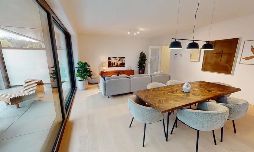 L'espace de vie de l'appartement témoin avec un coin salon, un coin repas et une terrasse